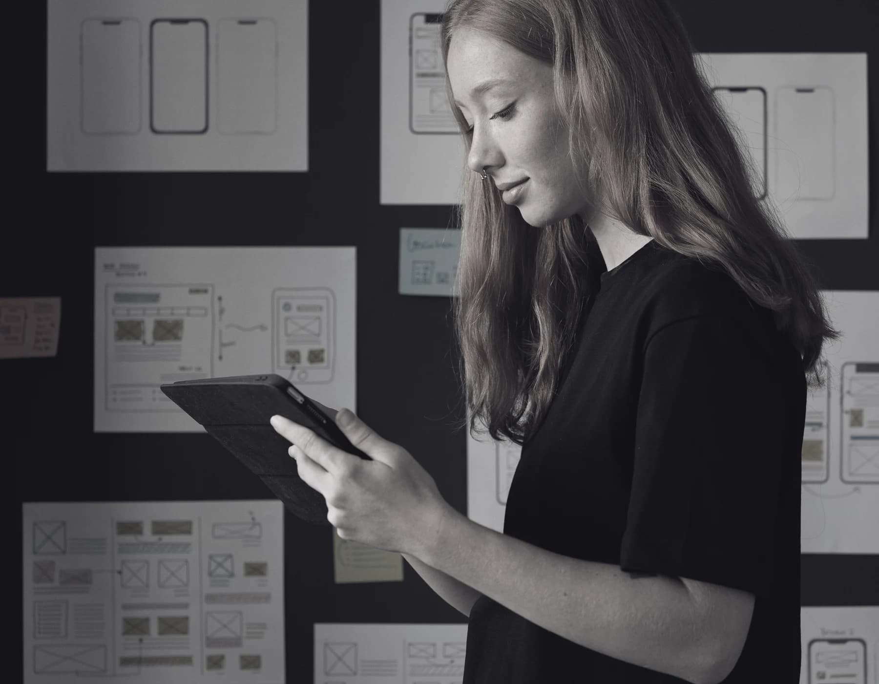A founder reviewing website wireframes on a tablet in front of a planning board.