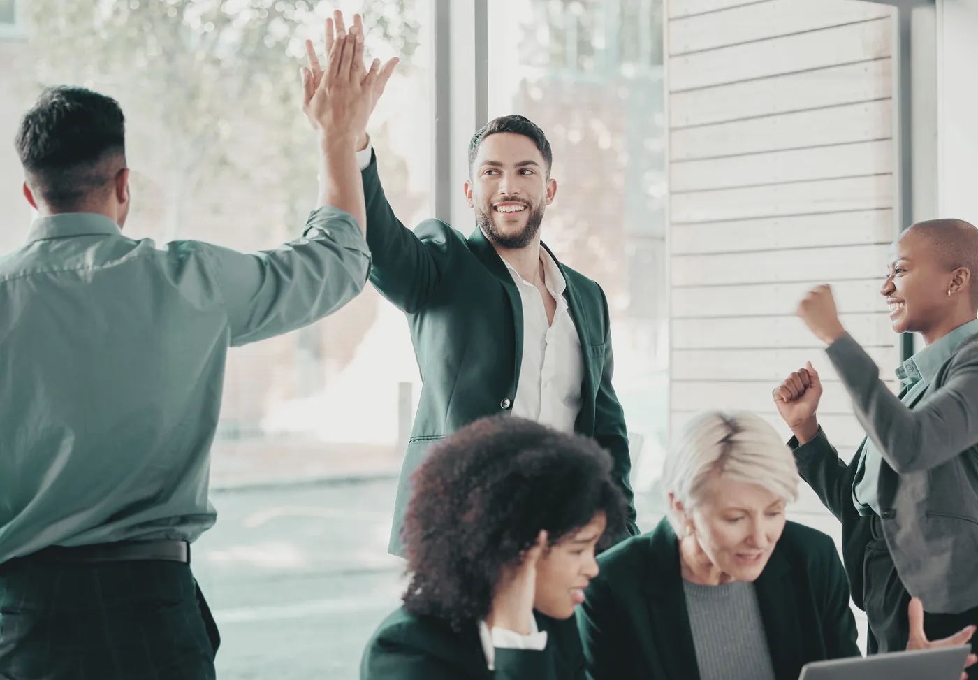 Colleagues celebrating with a high five in a bright office.