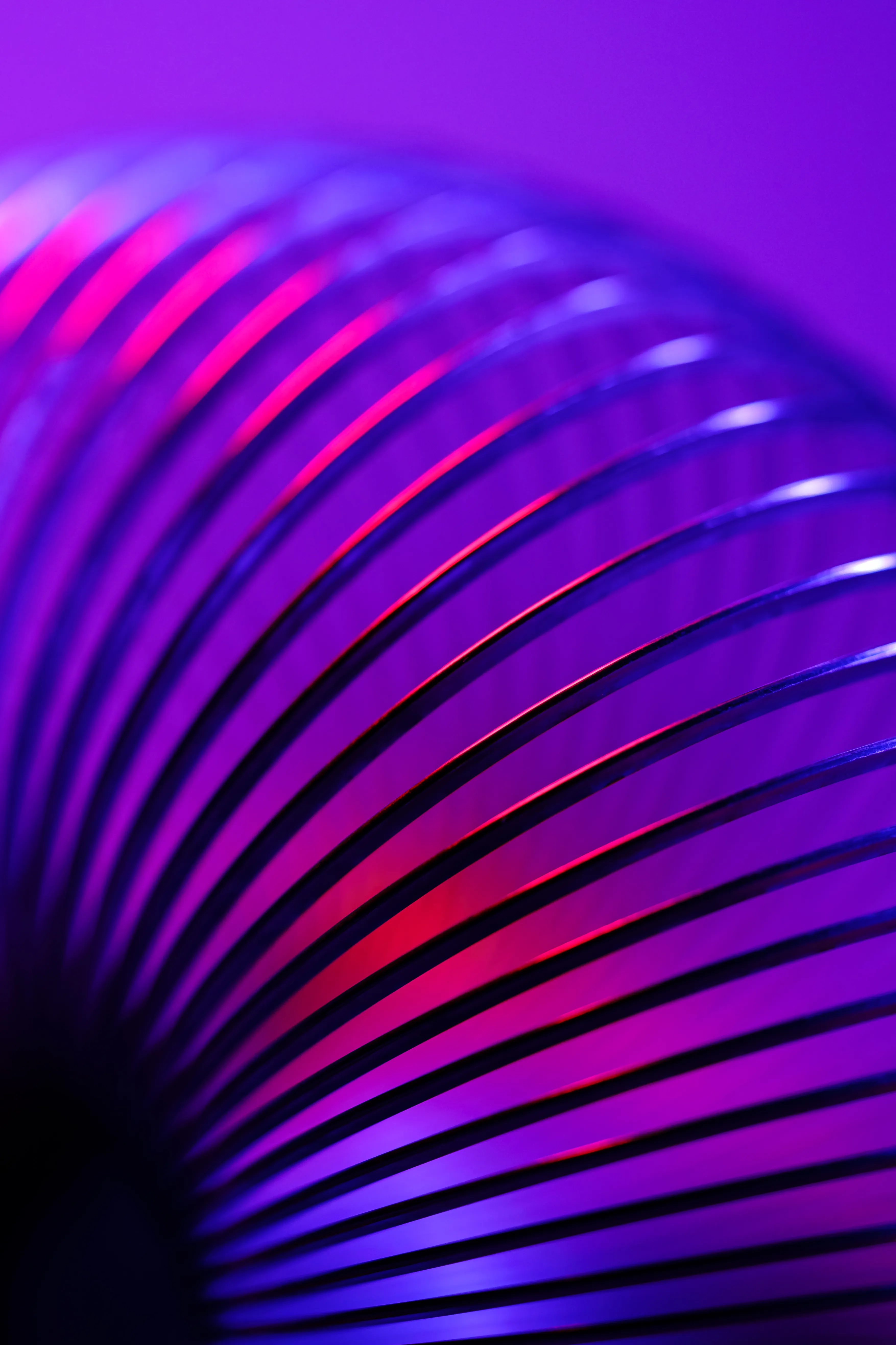 A close-up of a purple and pink neon-lit coiled spring.
