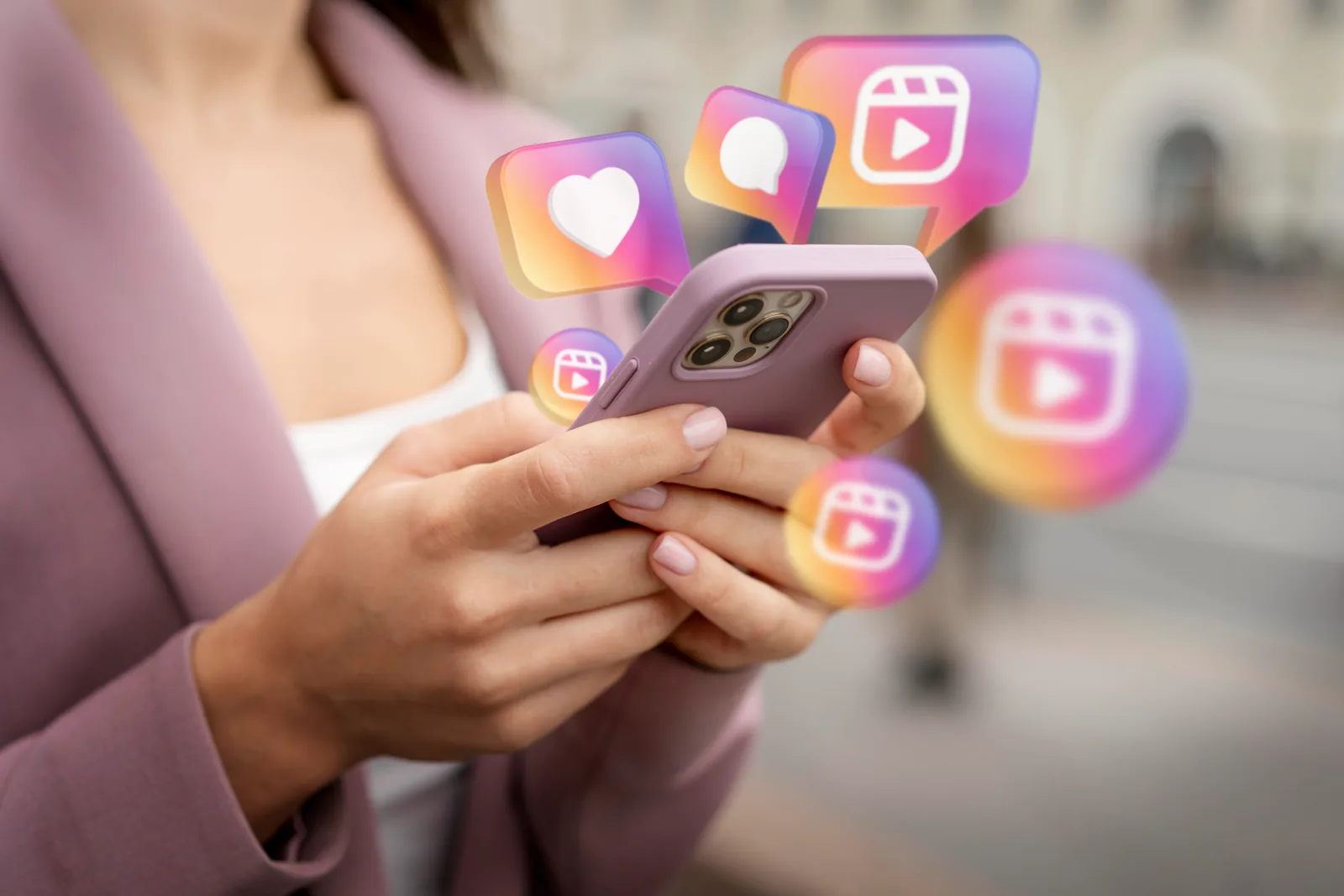 A woman holding a phone as heart, comment and Reels icons float up from the screen.