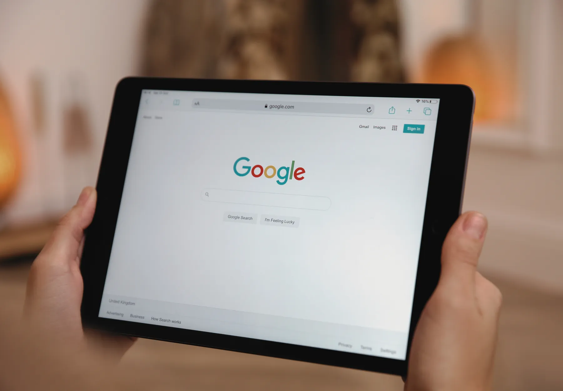Hands holding a tablet open on the Google search page.